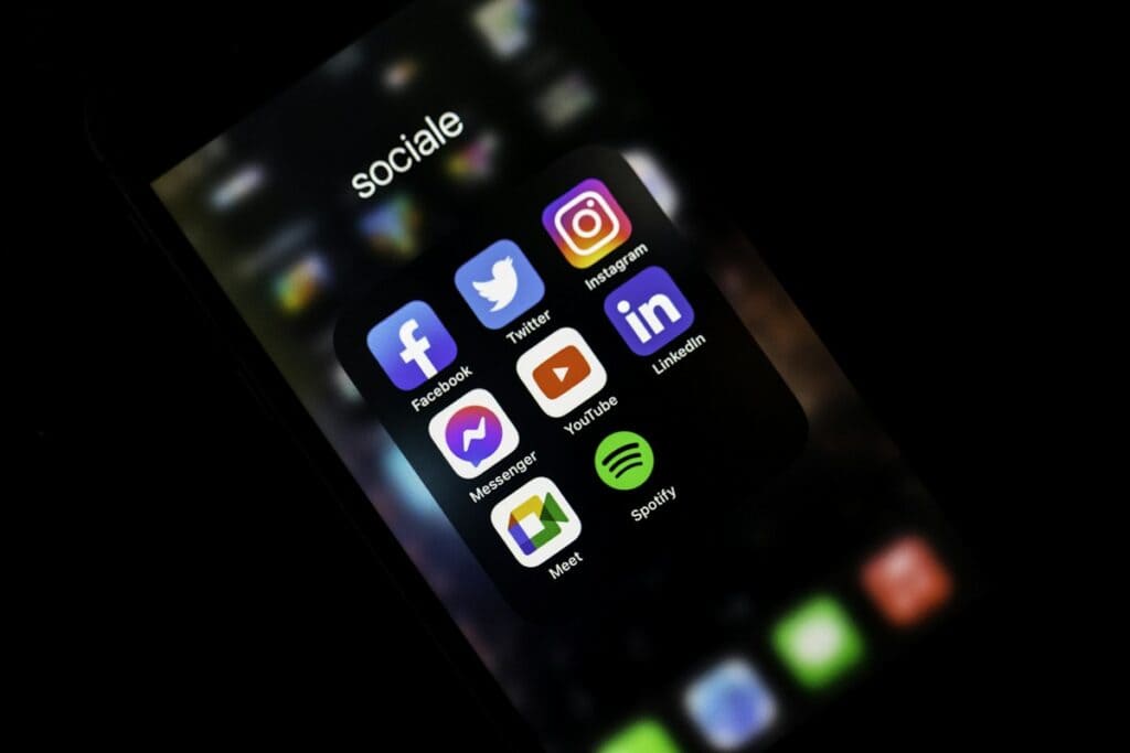 Smartphone screen showing social media app icons in a dark room