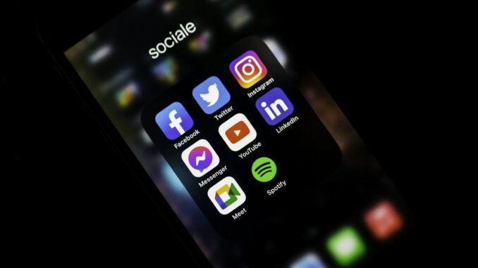 Smartphone screen showing social media app icons in a dark room