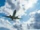 Passenger plane flying overhead through white clouds