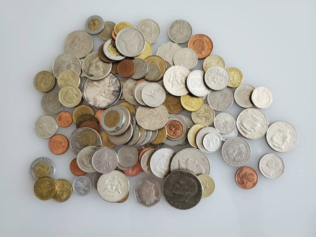 Pile of mixed coins from different countries on a white surface