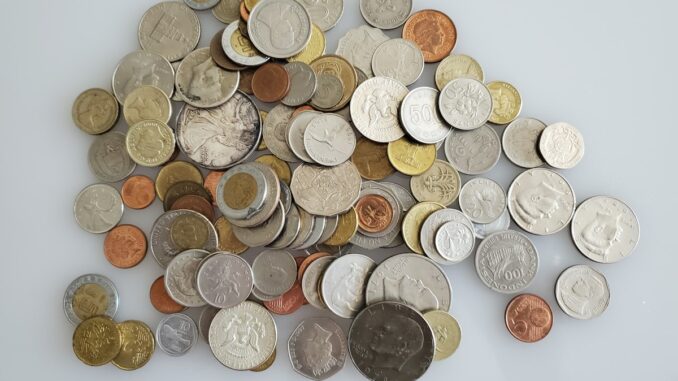 Pile of mixed coins from different countries on a white surface