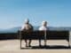 Older couple sitting on a seafront bench looking out to sea