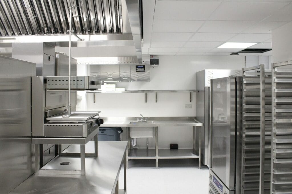 Stainless steel commercial kitchen with extraction hoods and prep counters