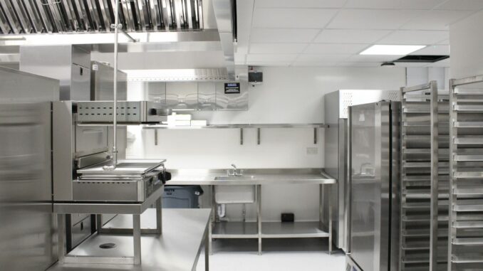 Stainless steel commercial kitchen with extraction hoods and prep counters