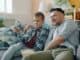 Father and son relaxing on a sofa watching television
