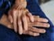 Close-up of an older person's hands resting together on their lap