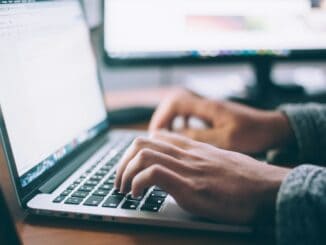 Hands typing on a laptop keyboard