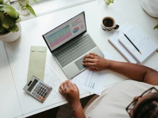 Person working on financial charts on a laptop at a desk
