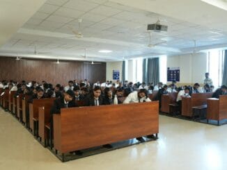 Rows of students seated at desks in a large hall