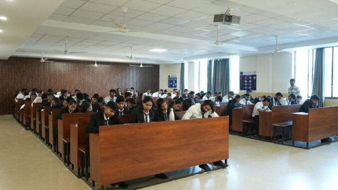 Rows of students seated at desks in a large hall