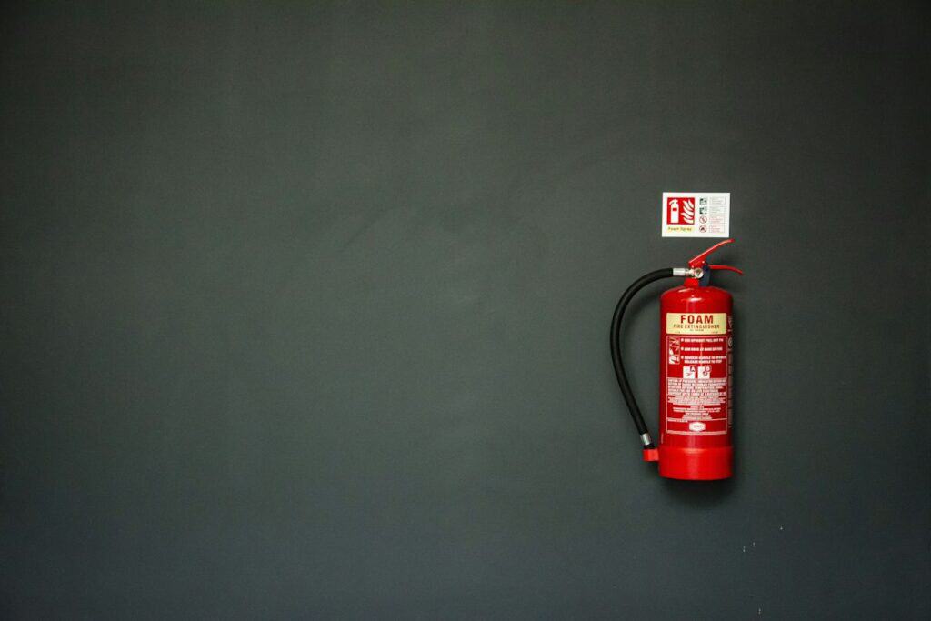 Red fire extinguisher mounted on a dark grey wall