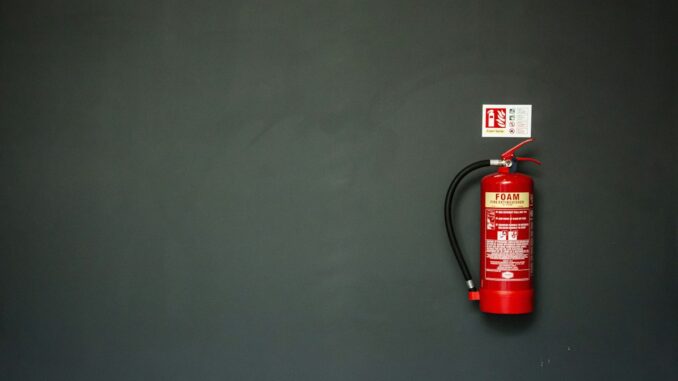 Red fire extinguisher mounted on a dark grey wall