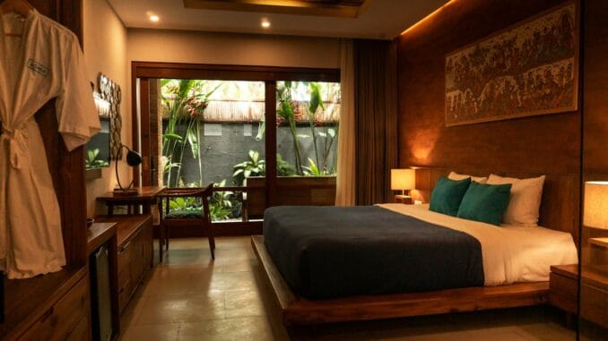 Warmly lit hotel bedroom with a made bed and wooden furnishings