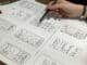 Hand sketching mobile app screen wireframes on paper