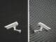 Two grey CCTV cameras mounted on the side of a building