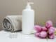 Rolled white towel, pump bottle, tealight and pink tulips on a spa table