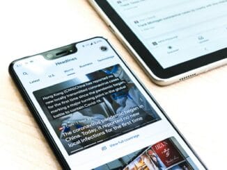 Smartphone showing a news app lying next to a tablet